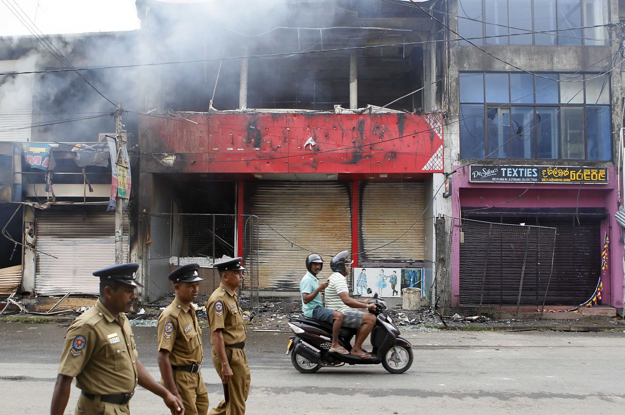Police officers on a street in Aluthgama as shops burn. A curfew was put in place to prevent further violence.