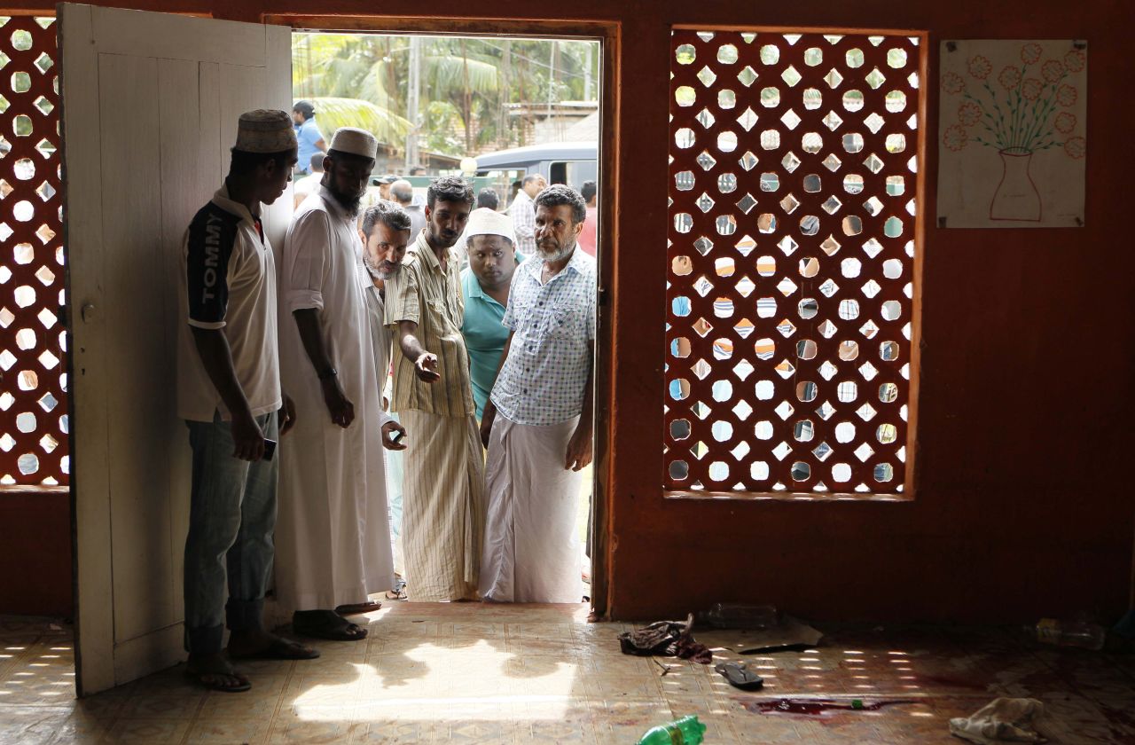Men point at blood on the floor of a home.