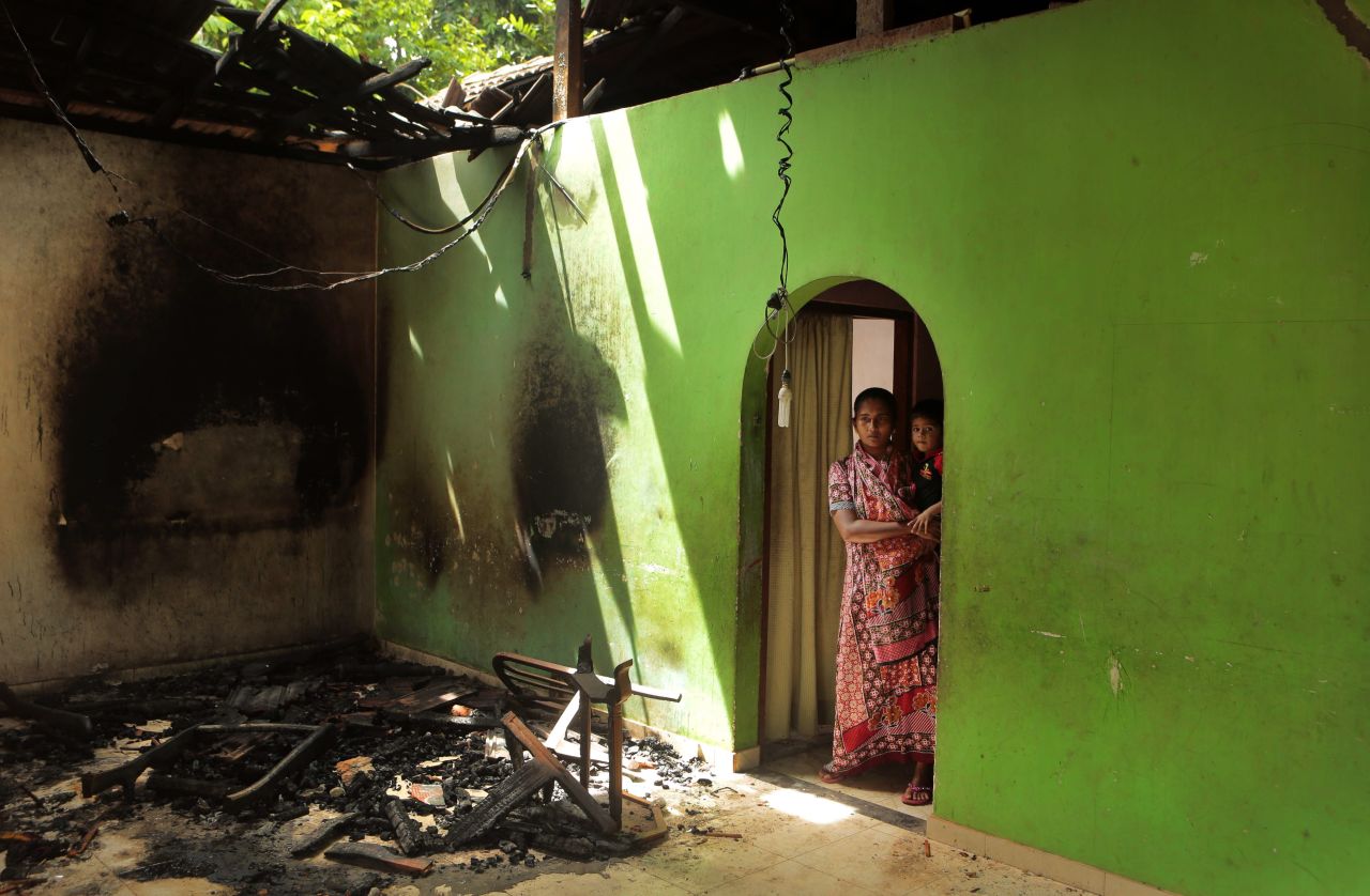 A Muslim mother and child take in damage to their house.