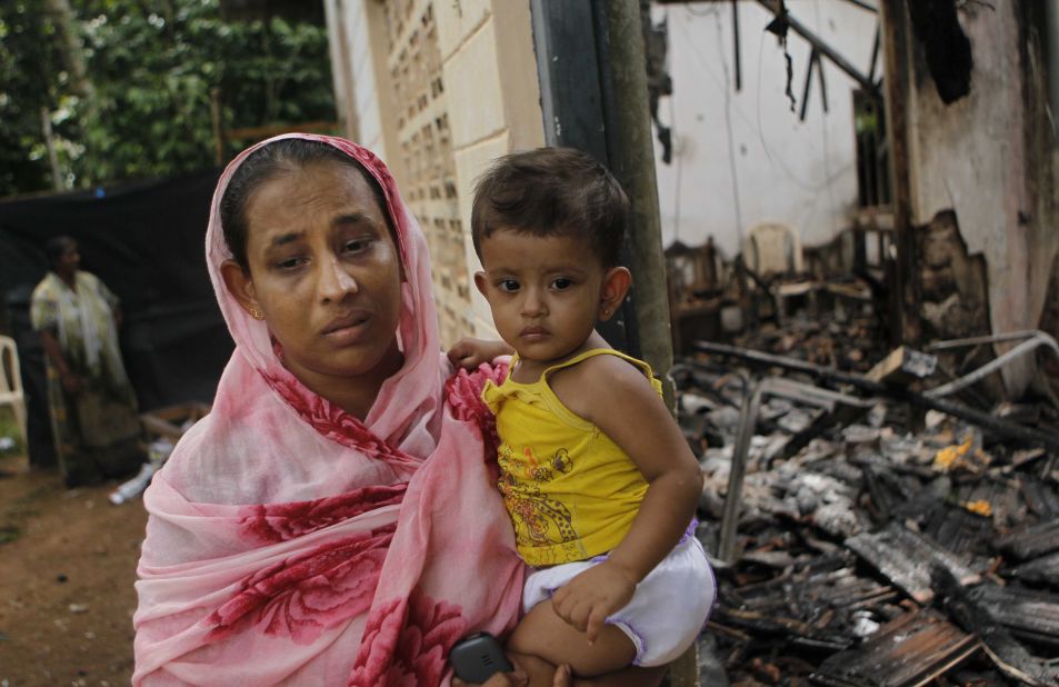 A Sri Lankan Muslim woman carries her daughter outside her burnt house after at least  three Muslims were killed and 80 injured in clashes with Buddhists last month. The sectarian riots in and around the town of Aluthgama, in southern Sri Lanka, followed demonstrations by the hardline Buddhist group Bodu Bala Sena, police said. Homes and shops were looted and burned.