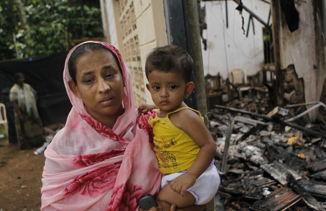 A Sri Lankan Muslim woman carries her daughter outside her burnt house after at least three Muslims were killed and 80 injured in clashes with Buddhists last month. The sectarian riots in and around the town of Aluthgama, in southern Sri Lanka, followed demonstrations by the hardline Buddhist group Bodu Bala Sena, police said. Homes and shops were looted and burned.