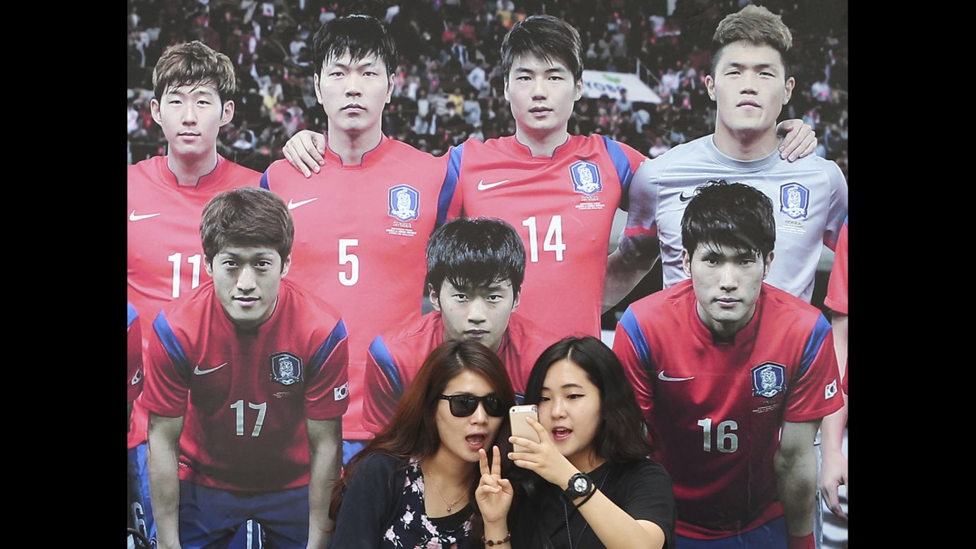 Women take a selfie in front of a picture of the South Korean national soccer team Monday, June 16, in Seoul, South Korea.