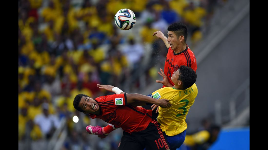 Mexican forwards Giovani Dos Santos, left, and Oribe Peralta try to win the ball with Thiago Silva in between them.