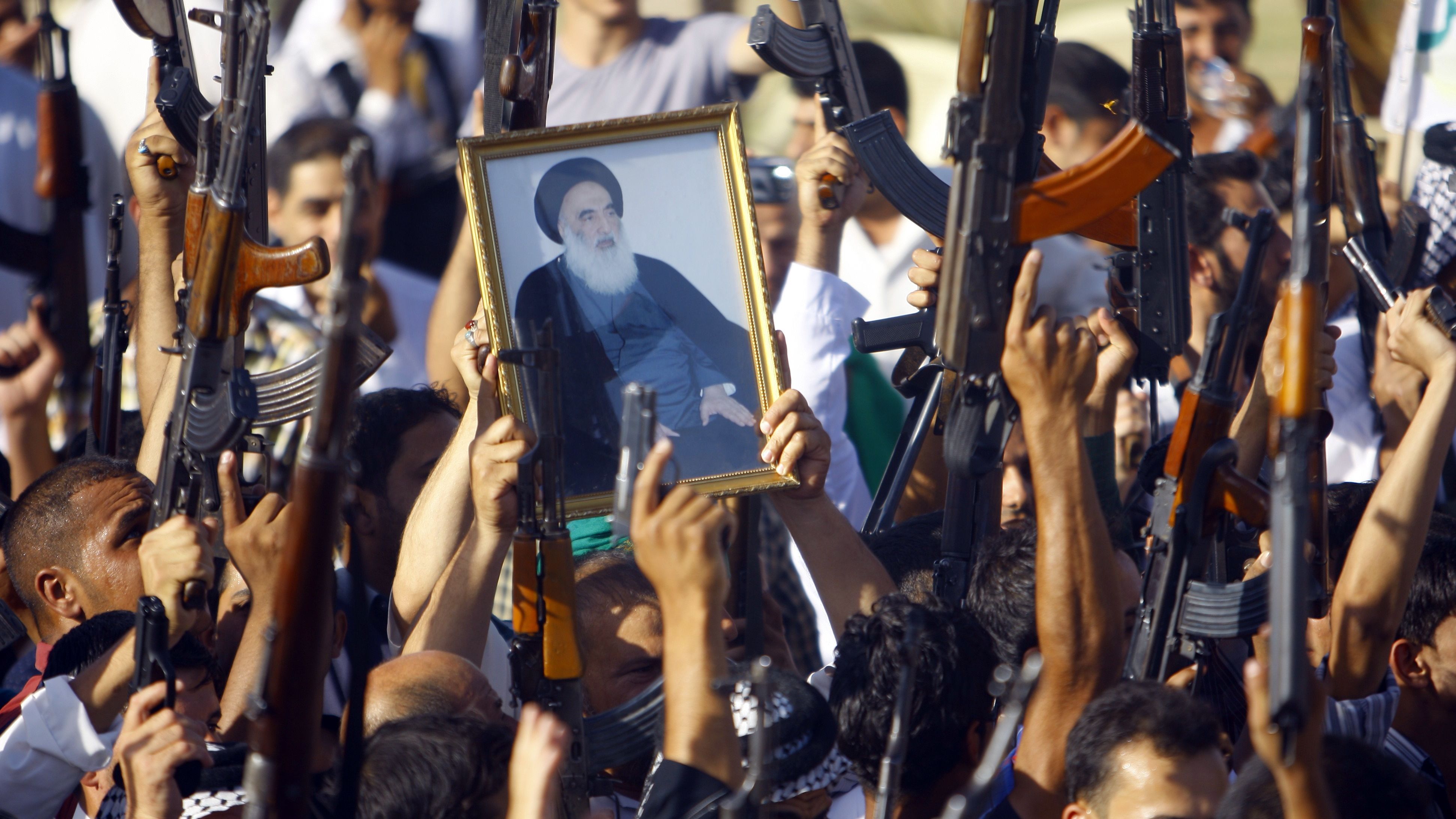 Iraqi Shiite tribesmen brandish their weapons and a poster of Shiite cleric Grand Ayatollah Ali al-Sistani in June 2014, as they gather to show their willingness to join Iraqi security forces in the fight against militants who'd taken over several northern Iraqi cities.