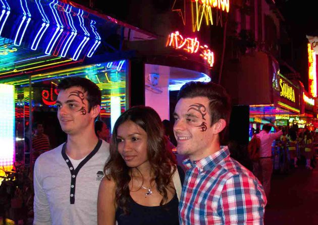 British tourists Cameron Johnson and his brother, Brad, accompanied by a Hangover Tour guide, on Soi Cowboy. The tattoo sticker "acts like a mask ... and you just forget about who you are back home, and you just sort of go with it," says Brad.