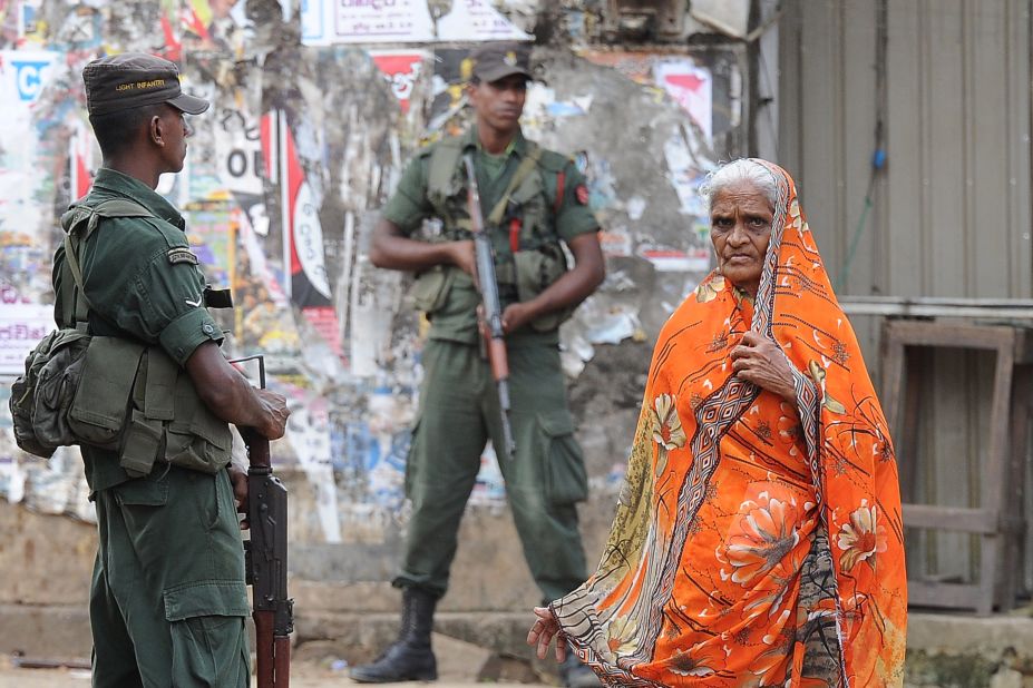 A Sri Lankan Muslim woman walks past soldiers following clashes between Muslims and Buddhists in the town of Aluthgama.