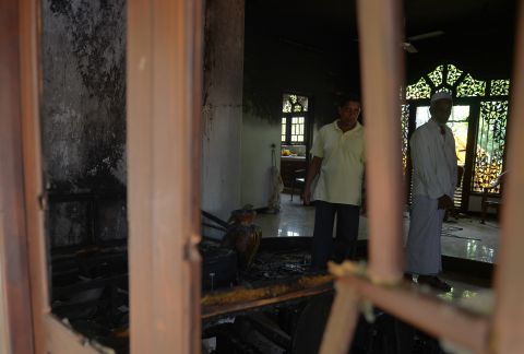 Sri Lankan residents survey the damage to a damaged Muslim-owned home.
