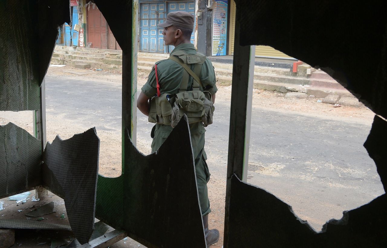 A soldier stands guard outside a smashed window.