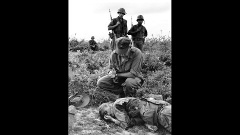 In this 1965 Henri Huet photograph, Chaplain John McNamara administers last rites to photographer Dickey Chapelle in South Vietnam. Chapelle was covering a U.S. Marine unit near Chu Lai for the National Observer when a mine seriously wounded her and four Marines. Chappelle died en route to a hospital, the first American woman correspondent ever killed in action.