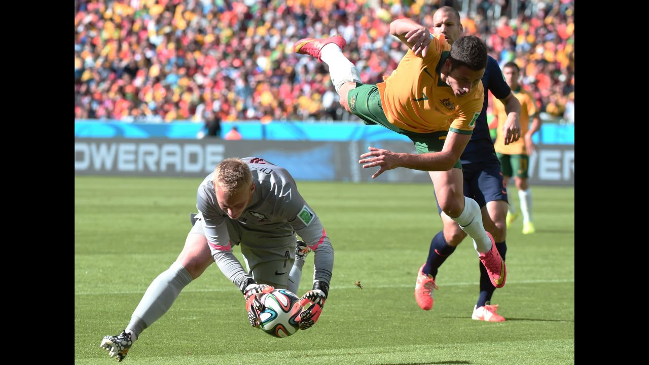Netherlands goalkeeper Jasper Cillessen corrals the ball while Australia's Mathew Leckie leaps through the air. 
