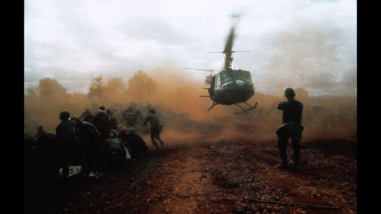 Tim Page photographed a U.S. helicopter taking off from a clearing near Du Co SF camp in Vietnam in 1965. Wounded soldiers crouch in the dust of the departing helicopter. The military convoy was on its way to relieve the camp when it was ambushed.
