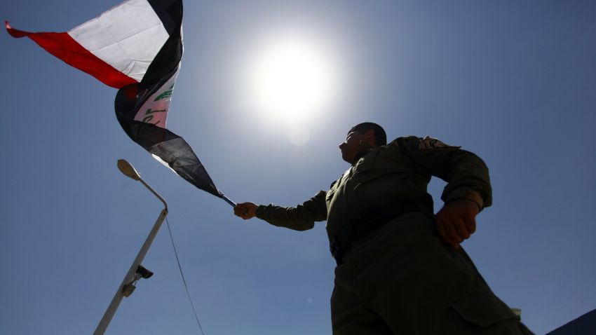 A member of Iraq's security forces wave his national flag as newly recruited men gather (unseen) on June 18 2014 in the southern Shiite Muslim shrine city of Najaf following top Shiite cleric Grand Ayatollah Ali al-Sistani's call for Iraqis to take up arms against 'terrorists' who have overrun swathes of the country in a major offensive.