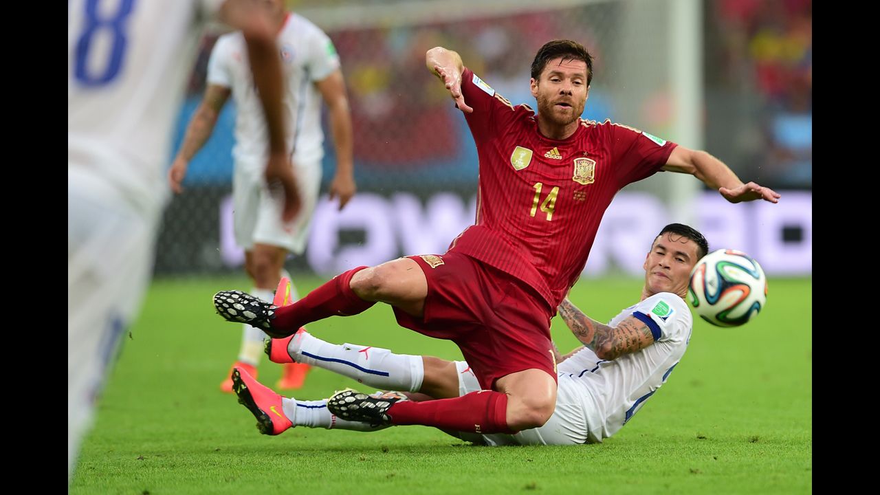 Spanish midfielder Xabi Alonso, left, falls to the ground near Chilean midfielder Charles Aranguiz.