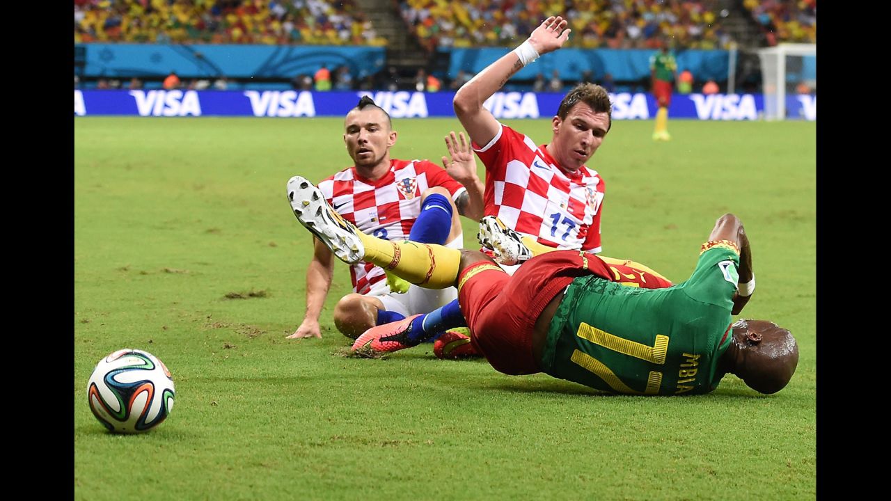 Cameroon's Stephane Mbia falls to the ground as he is challenged by Croatia's Danijel Pranjic, left, and Mario Mandzukic.
