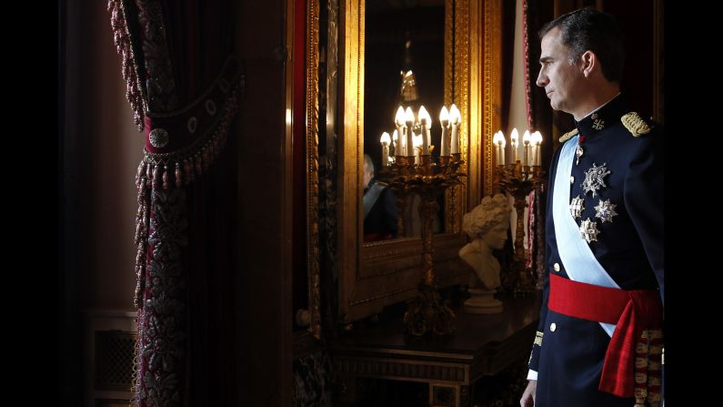 The new King walks toward the balcony of the royal palace to wave to the crowd.