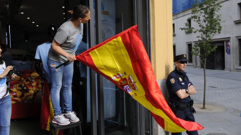 Store attendants put up Spanish flags in Madrid.