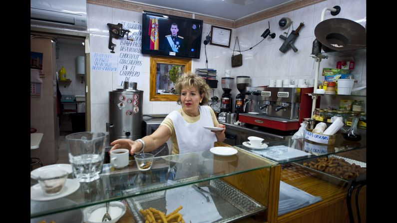 A woman works in Pamplona, Spain, as Felipe speaks on television.