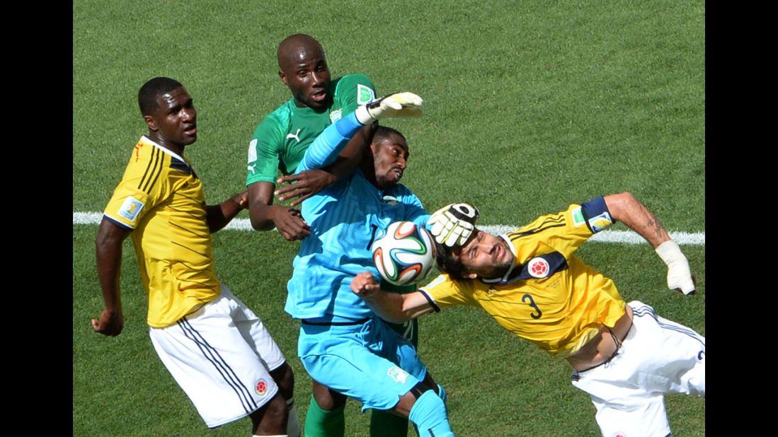 Ivory Coast goalkeeper Boubacar Barry, center, fights for the ball with Colombia defender Mario Yepes, right.
