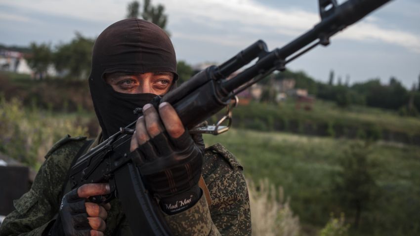 A pro-Russian fighter holds a gun during a handover of the bodies of Ukrainian troops killed in a plane shot down near Luhansk, at a check point in the village of Karlivka near Donetsk, eastern Ukraine, Wednesday, June 18, 2014.