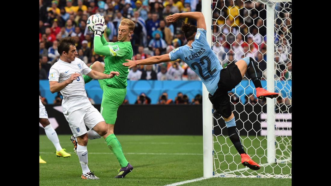 Hart makes a save as Uruguay defender Martin Caceres flies past the goal.