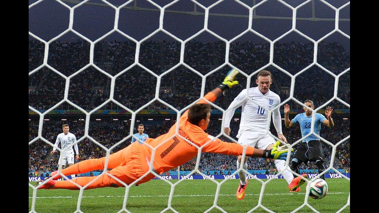 England forward Wayne Rooney taps the ball past Uruguay goalkeeper Fernando Muslera to tie the match at 1-1. It was Rooney's first World Cup goal in his career.