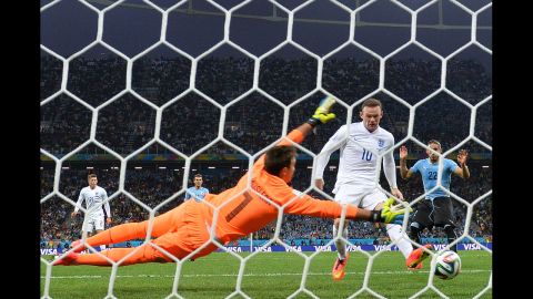 England forward Wayne Rooney taps the ball past Uruguay goalkeeper Fernando Muslera to tie the match at 1-1. It was Rooney's first World Cup goal in his career.