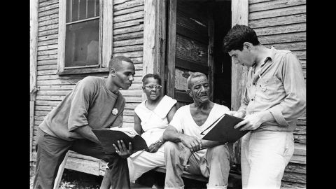 Johnny Waters, Ceola Wallace and Jake Plum explain registration procedures to prospective voter Willie McGee in Hattiesburg, Mississippi.