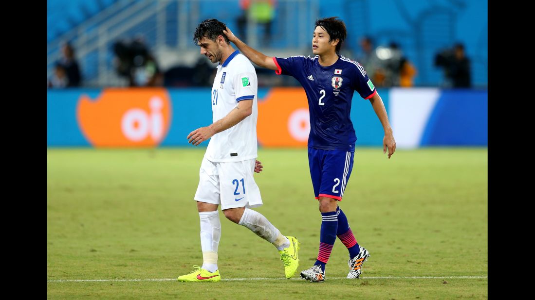 Konstantinos Katsouranis of Greece is consoled by Atsuto Uchida of Japan after he received a red card.
