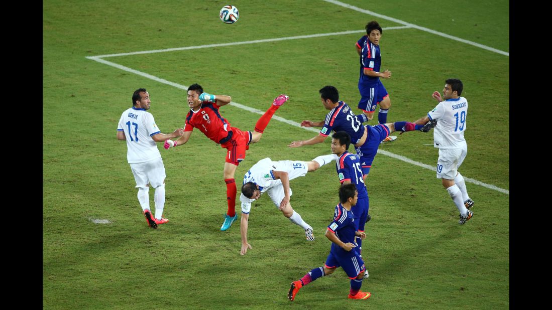Goalkeeper Eiji Kawashima of Japan punches the ball clear as Vasilis Torosidis of Greece and Maya Yoshida of Japan collide.