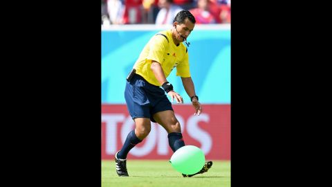 Referee Enrique Osses tries to catch a balloon that came onto the field.