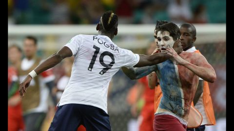 French midfielder Paul Pogba reaches out to a team supporter who ran onto the field at the end of France's World Cup match against Switzerland in Salvador, Brazil. France thrashed Switzerland 5-2 to go atop Group E.