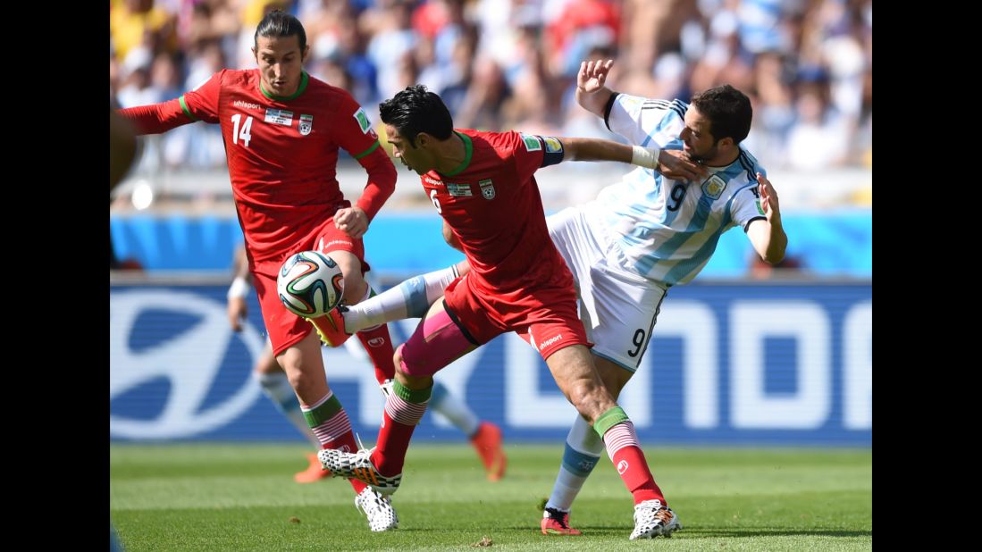 Iran midfielders Andranik Teymourian and Javad Nekounam battle for the ball against Argentina forward Gonzalo Higuain.  