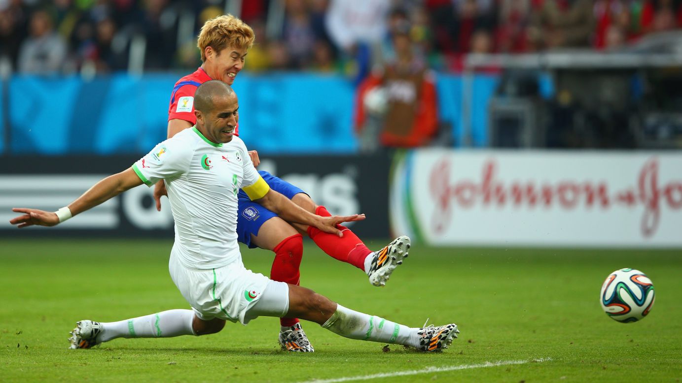 Son Heung-min of South Korea scores his team's first goal past Madjid Bougherra of Algeria.