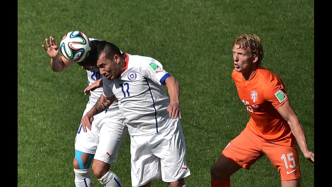 Chile defender Gary Medel, center, heads the ball next to his teammate Charles Aranguiz, left, and Netherlands forward Dirk Kuyt.