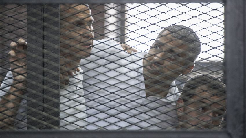 Al-Jazeera news channel's Australian journalist Peter Greste (L) and his colleagues, Egyptian-Canadian Mohamed Fadel Fahmy (C) and Egyptian Baher Mohamed , listen to the verdict inside the defendants cage during their trial for allegedly supporting the Muslim Brotherhood on June 23, 2014 at the police institute near Cairo's Tora prison.