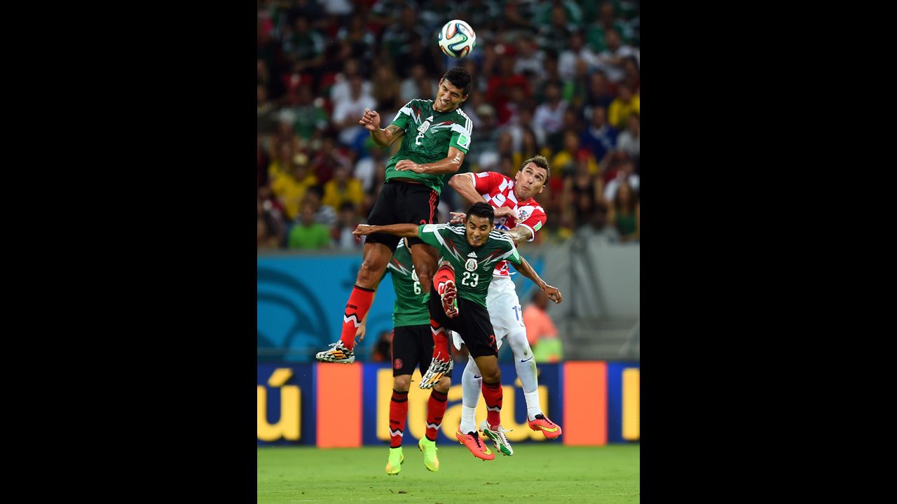 Francisco Javier Rodriguez (in green) of Mexico goes up for a header against Mario Mandzukic (in red and white) of Croatia.
