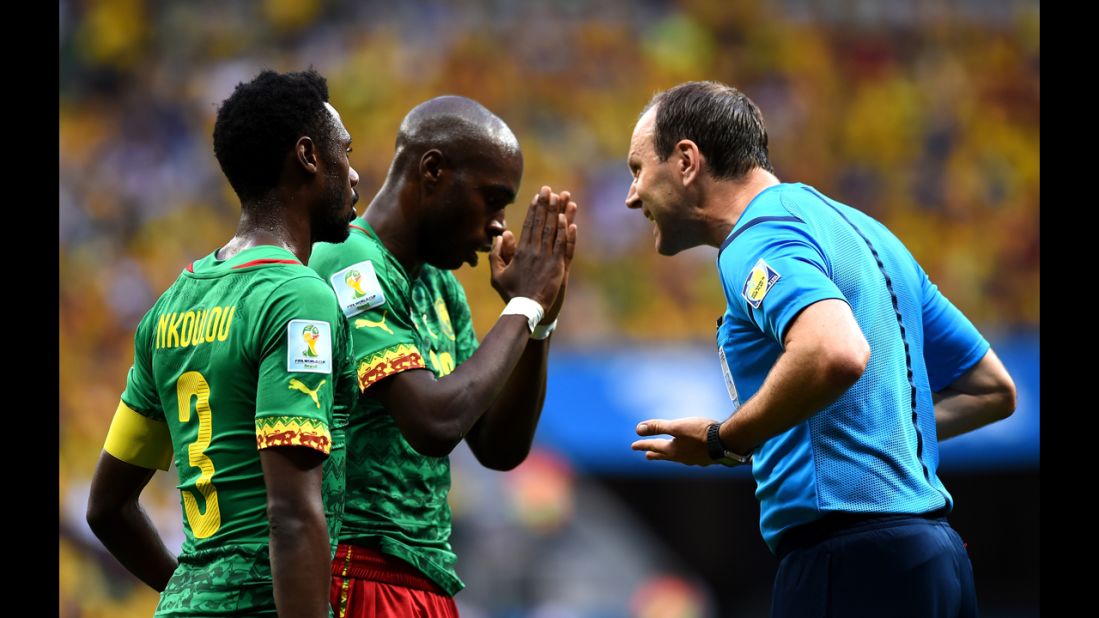 Referee Jonas Eriksson, right, speaks to Allan Nyom, center, of Cameroon.