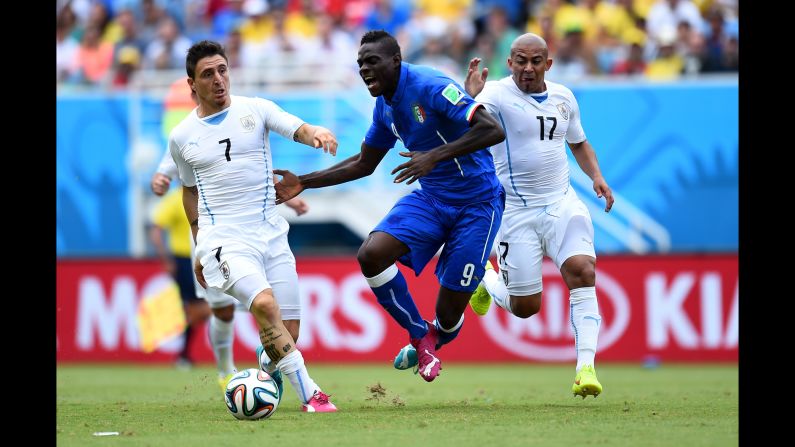 Mario Balotelli of Italy competes for the ball against Cristian Rodriguez, left, and Egidio Arevalo Rios, right, of Uruguay. 