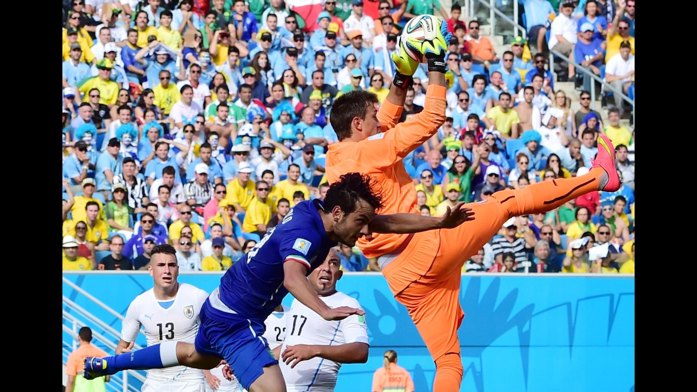 Uruguay goalkeeper Fernando Muslera grabs the ball away from Italy's Marco Parolo. 