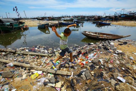 A Chinese boy runs along the trash-strewn beach along the sea coast in Anquan village, which is in Hainan province, in 2011.