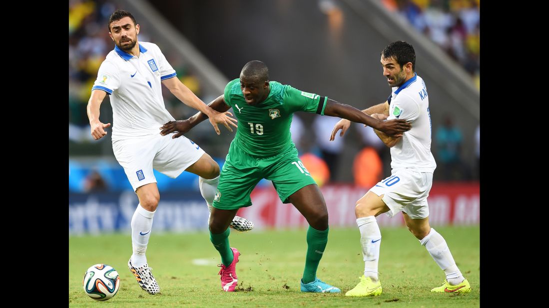 Yaya Toure of the Ivory Coast is challenged by Giannis Maniatis, left, and Giorgos Karagounis of Greece.