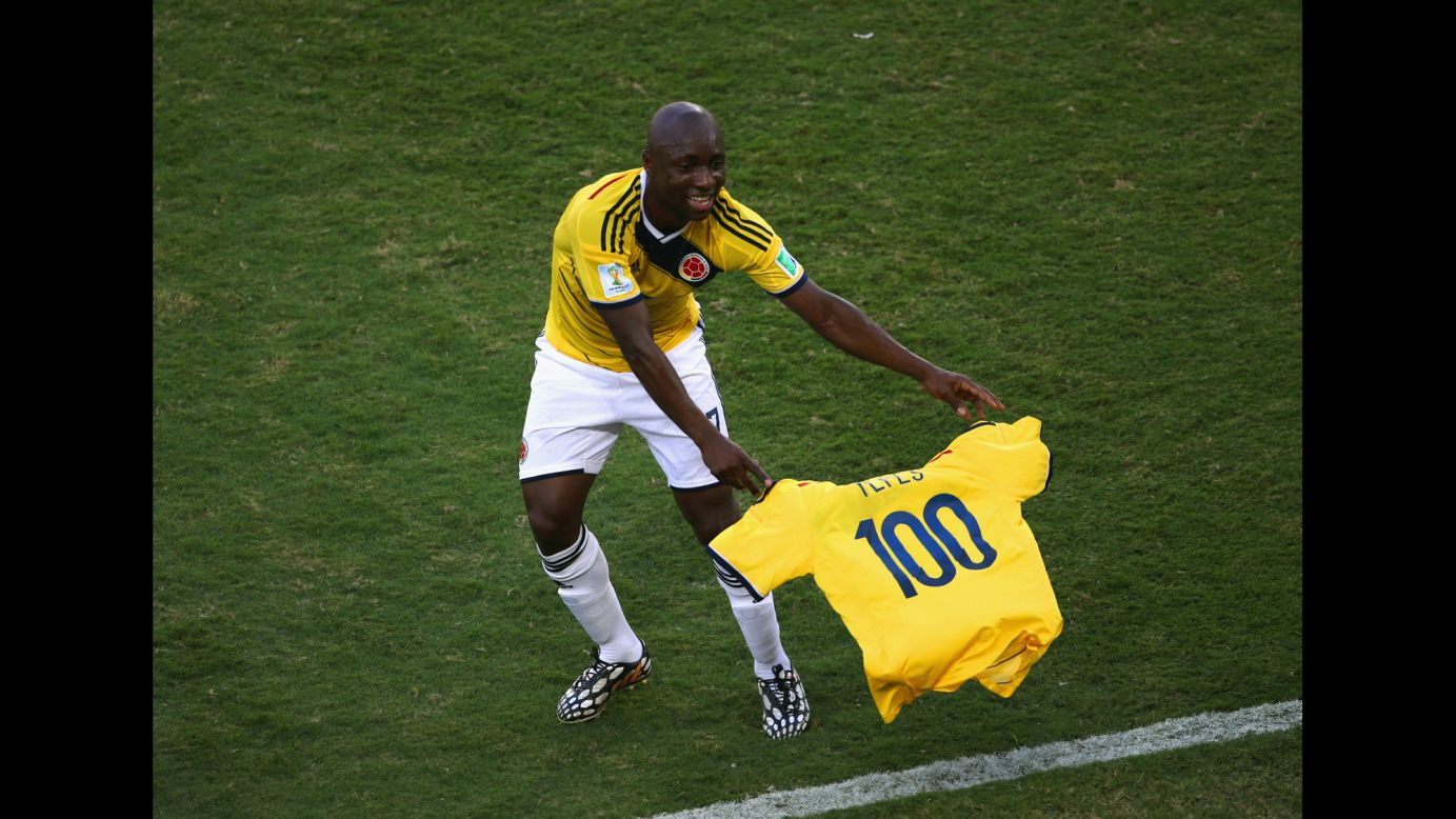 Pablo Armero of Colombia holds up a shirt with the number 100 during the match against Japan.
