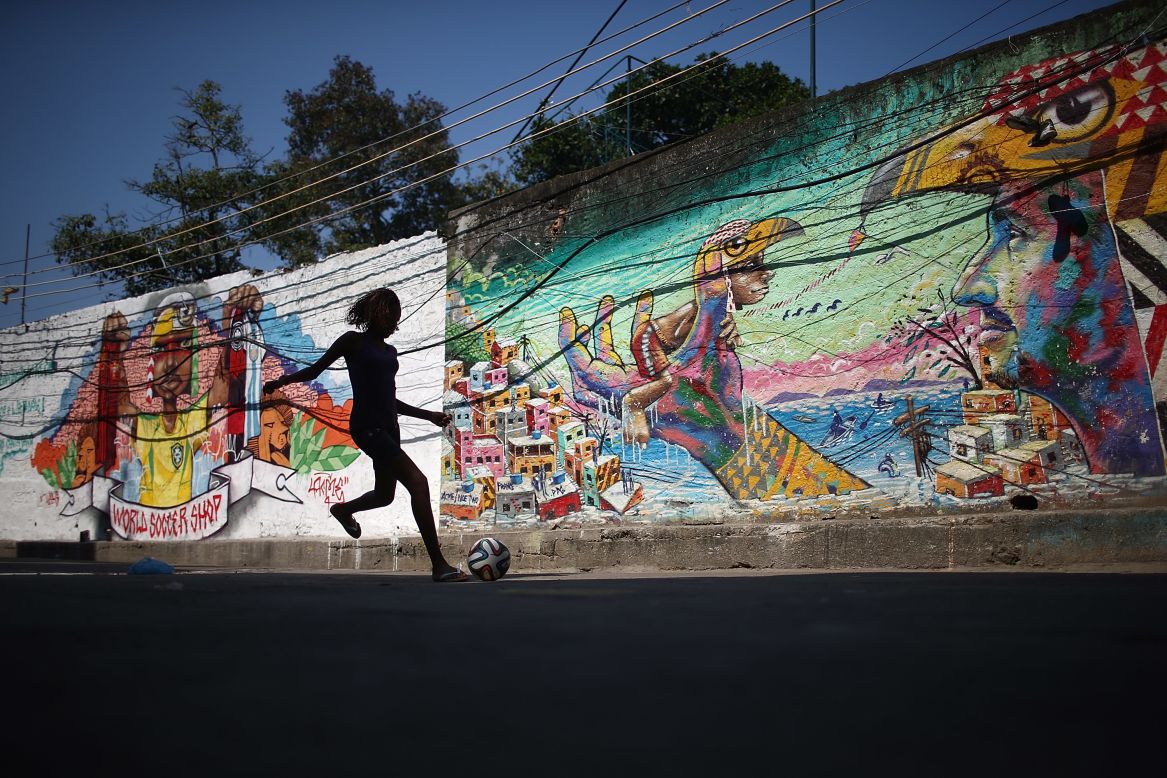 A girl kicks a football in front of graffiti created by acclaimed artist Acme in the pacified Pavao-Pavaozinho community in Rio de Janeiro, Brazil. <br /><br />Another issue at the heart the protests has been the occupation and "pacification" of some of the poorest slums in Brazil by the police and military in an attempt to reduce crime during the tournament. 