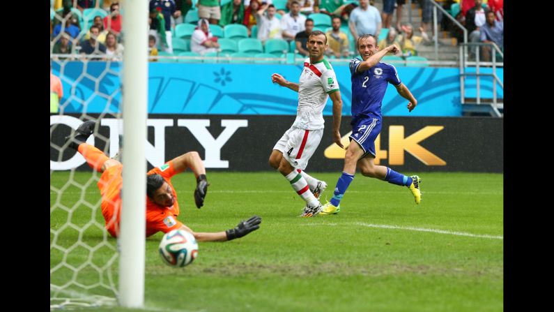 Avdija Vrsajevic of Bosnia-Herzegovina shoots and scores his team's third goal past goalkeeper Alireza Haghighi of Iran during a match in Salvador, Brazil, on June 25. Bosnia-Herzegovina won 3-1.
