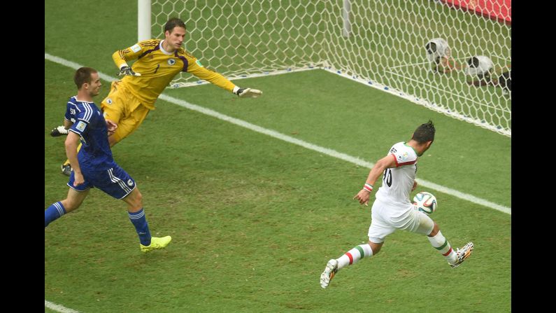 Iran forward Reza Ghoochannejhad, right, kicks to score his team's first goal past Bosnia-Herzegovina goalkeeper Asmir Begovic as Bosnia-Herzegovina defender Toni Sunjic runs during the match.