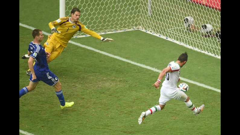 Iran forward Reza Ghoochannejhad, right, kicks to score his team's first goal past Bosnia-Herzegovina goalkeeper Asmir Begovic as Bosnia-Herzegovina defender Toni Sunjic runs during the match. 