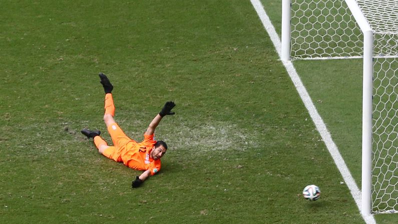 Goalkeeper Alireza Haghighi of Iran dives in vain after Emir Spahic of Bosnia-Herzegovina shoots and scores his team's first goal. 