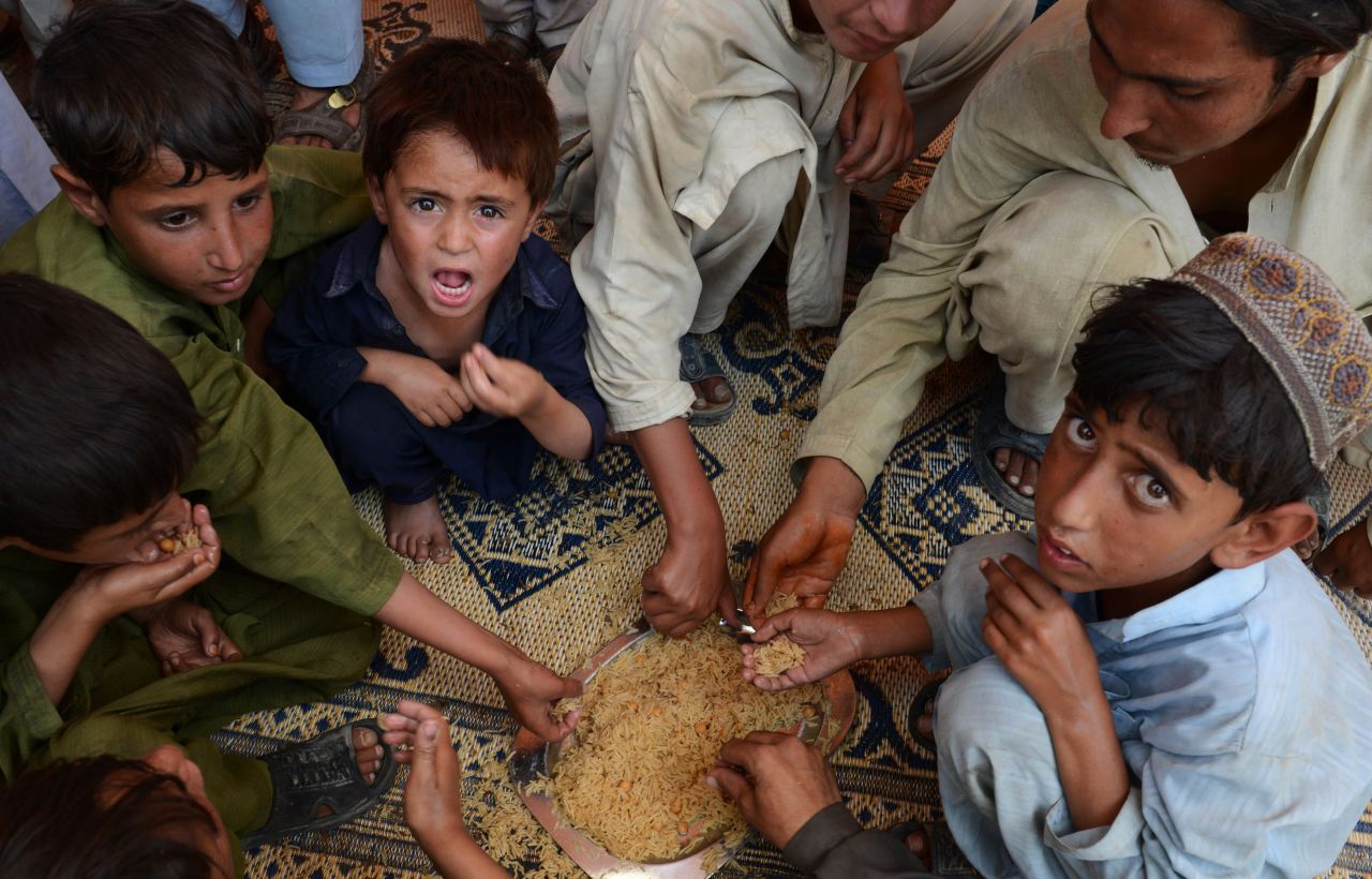 Hungry Pakistani children eat rice together on their arrival in Bannu.