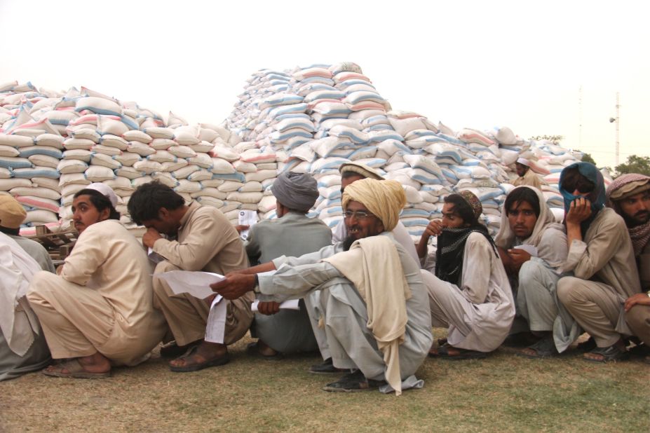 Sacks of wheat are heaped in mounds in the center of the distribution point.