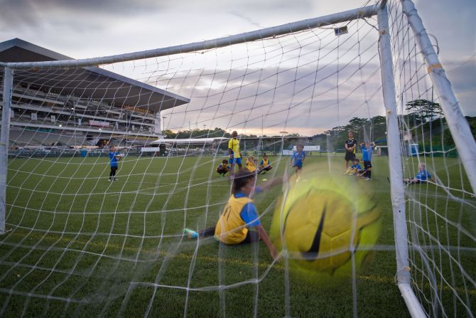A ball <a href="index.php?page=&url=http%3A%2F%2Fireport.cnn.com%2Fdocs%2FDOC-1143657">flies into the net</a> during a youth training session in Singapore. "Parents hide in the shade while kids run around for hours. Hard to understand how can they take so much sun. They must be crazy about football," said Catanescu.